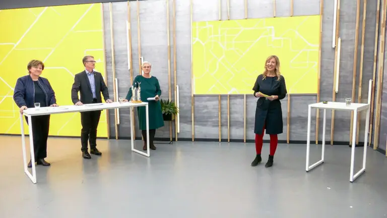 Hybridveranstaltung im Streamingstudio Moderatorin mit drei Livegästen am gemeinsamen Stehtisch und Zuschaltung weiterer Teilnehmer durch LED-Wand mit neuester Technik