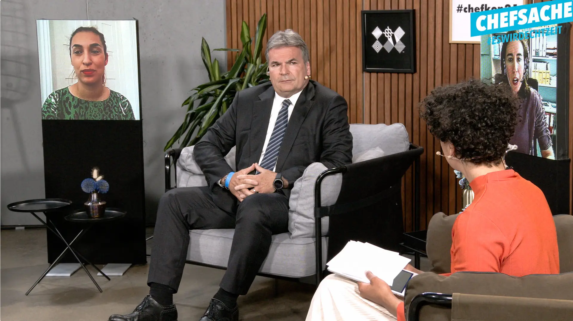 Hybride Veranstaltung im Interview Konferenzformat, Moderatorin und ein Interviewpartner sitzen einander zugewandt im Studio zwei weitere Teilnehmerinnen sind per Bildschirm in die Runde zugeschaltet