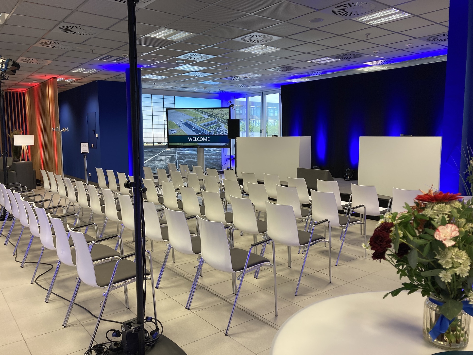 Flughafen Leipzig-Halle Eventlocation Terminal Lounge, Reihenbestuhlung vor Buhne mit zwei Stehpulten, Lichttechnik und Veranstaltungstechnik